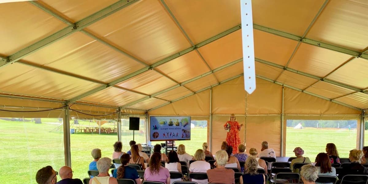 Kerry Sutcliffe speaking at the Chatsworth Estate Wellness Festival, with the audience listening under the marquee