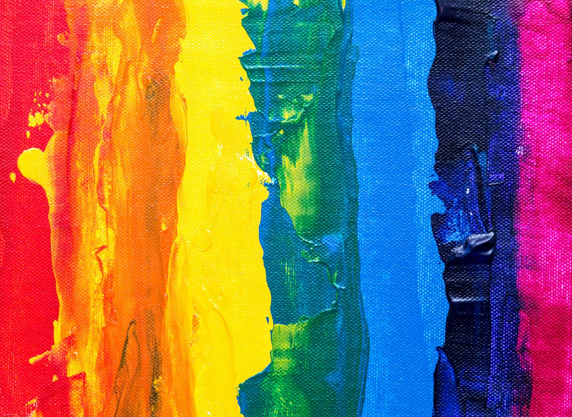 Close-up of vivid rainbow-coloured paint strokes on canvas